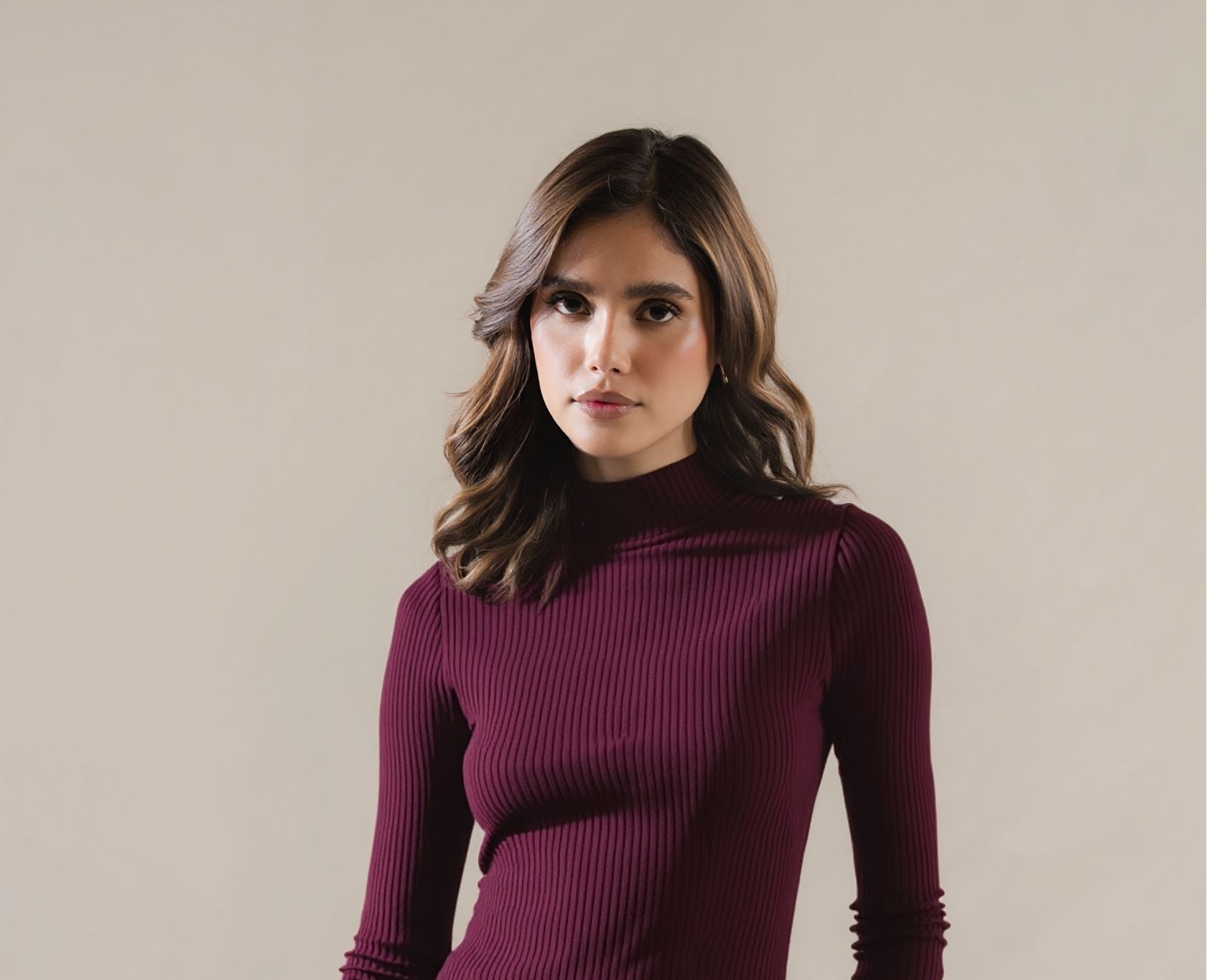 Woman wearing a maroon ribbed sweater against a plain background