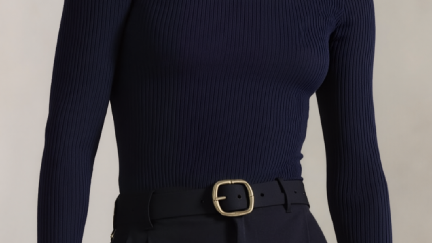 Person wearing a navy ribbed long-sleeve top with a belt against a neutral background